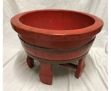 Large red painted Chinese wooden bowl, brass ring bound raised on four feet. 36 h x 53cms w. Condition ReportSome paint wear 