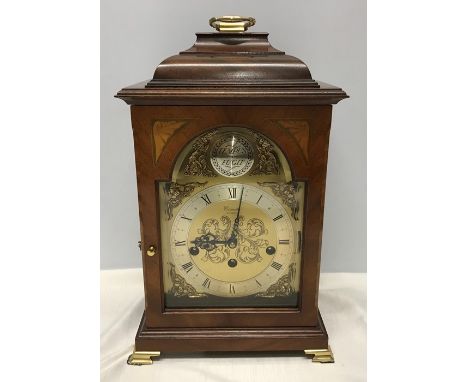 A mahogany reproduction mantle clock with inlay to front. Decorative brass face. Comitti of London. Westminster chimes, 34cms