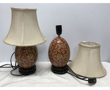 Pair of Chinese pottery gilt and red floral and leaf pattern table lamps, egg shaped oval, on carved wooden base stands, with