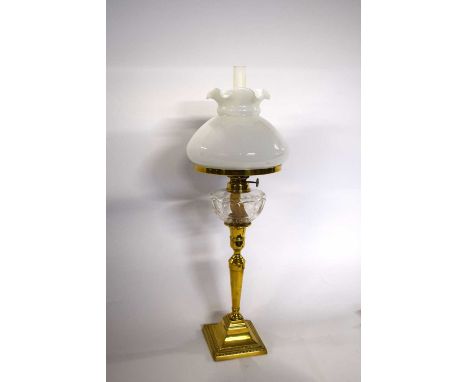 A brass oil lamp with white glazed shade and glass reservoir together with a brass Art Nouveau paperweight