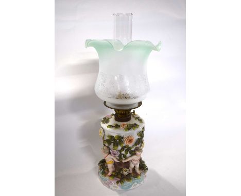 Late 19th Century continental porcelain lamp base with shade, the reservoir supported by four cherubs