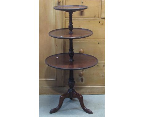 An Edwardian three tier graduated dumb waiter in the Georgian manner with turned columns and tripod base 