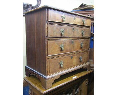 A small Georgian walnut chest of four long graduated drawers, with cross banded detail, quarter panelled top and raised on br