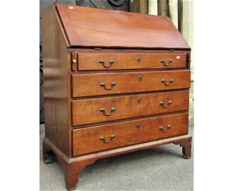 A Georgian countrymade bureau in fruit wood, the front elevation enclosed by four long graduated drawers, the fall flap revea