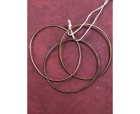 An interlinked bangle of three coloured 9ct gold rings. Weight 20g