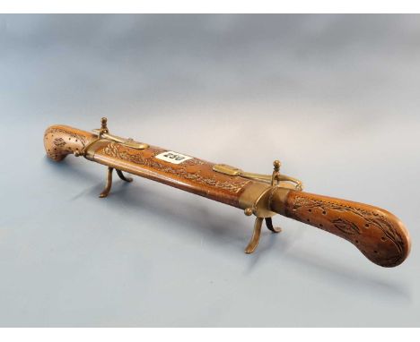 An Indian carving knife and fork fitting into each end of a carved wood sheath with brass mounts and feet