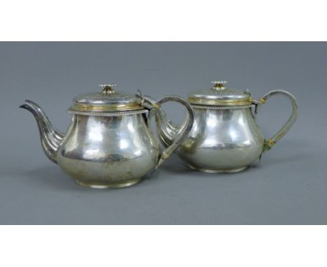 A pair of Georgian silver teapots. 13 cm high. 37.2 troy ounces. This lot has a current ivory exemption certificate.