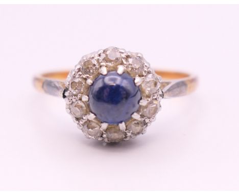 An 18 ct gold and platinum cabochon sapphire and diamond cluster ring. Ring size Q.