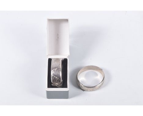 TWO ELIZABETH II HINGED SILVER BANGLES, both with foliate engraved scrolls to one half, Birmingham 1969 and 1988, gross weigh