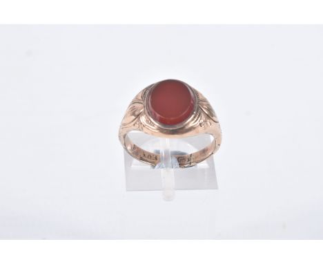 A GENTS SIGNET RING, of an oval form, set with an oval carnelian panel, collet set to the textured shoulders and polished ban