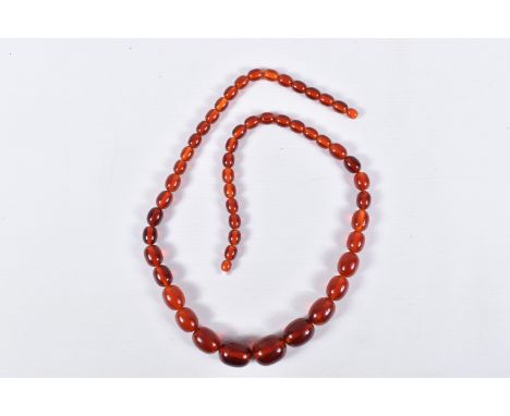 A STRING OF GRADUATED BAKELITE BEADS, graduating light red oval beads, largest measuring 25.4mm x 20.9mm, smallest measuring 