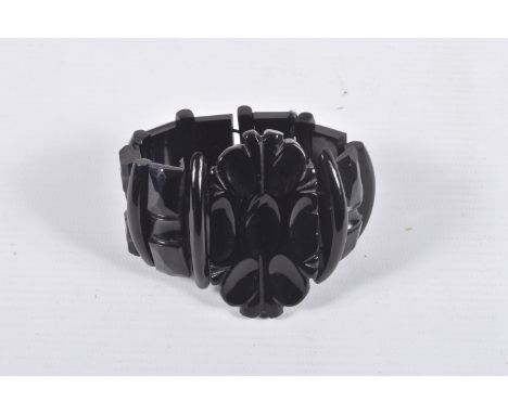A CARVED JET STRETCH LINK BRACELET, large carved oval centre and carved links, all fitted onto a black cord, approximate gros