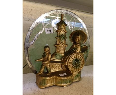 An Art Deco gold painted metal table lamp, modelled as Chinese figures in a rickshaw with a tower behind with original glass 