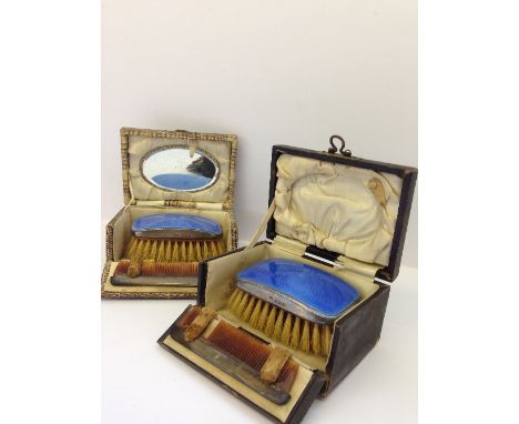 A pair of Art Deco silver and enamel hair brushes and comb sets in original travelling cases.