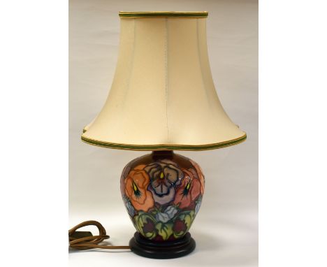 MODERN MOORCROFT TABLE-LAMP with red reserve and decorated with tube-lined flowers all-round, complete with shade and on a wo