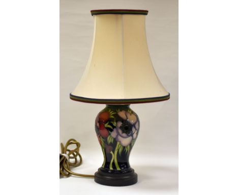 A MODERN MOORCROFT TABLE LAMP decorated with tube-line flowers and stems on a blue ground, complete with shade and on a woode