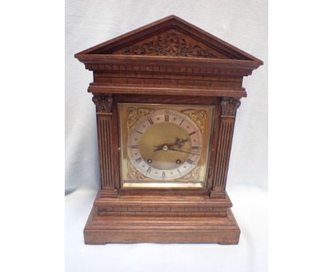 AN EDWARDIAN OAK MANTEL CLOCK OF ARCHITECTURAL FORM with brass and silvered dial with ' W&amp;H' movement, striking on two go
