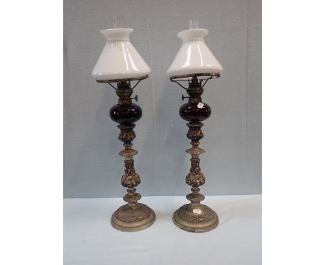 A PAIR OF 19TH CENTURY SILVER PLATED ON COPPER CANDLESTICKS fitted with 'piano lamps', with ruby glass fonts and white shades