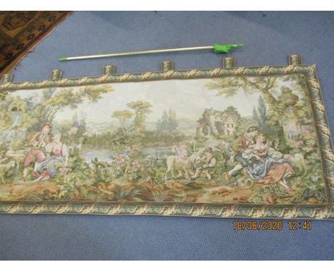 A reproduction machine made wall tapestry depicting a continental scene with lovers in the foreground and a watermill in the 