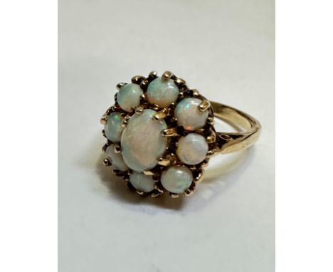 A 9ct gold water opal cluster ring, the oval centre stone in claw setting surrounded by eight circular water opals mounted in