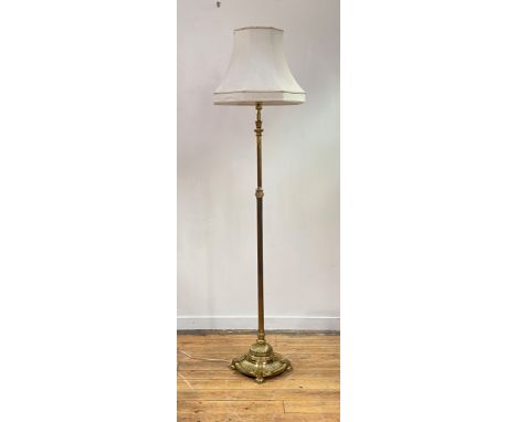An early 20th century cast brass telescopic lamp standard, the reeded column over circular gadrooned base standing on four su