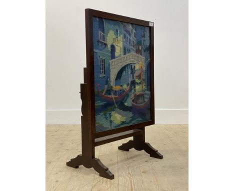 An early 20th century metamophic table / fire screen, with glazed needlework panel depicting a Venetian waterway H79cm