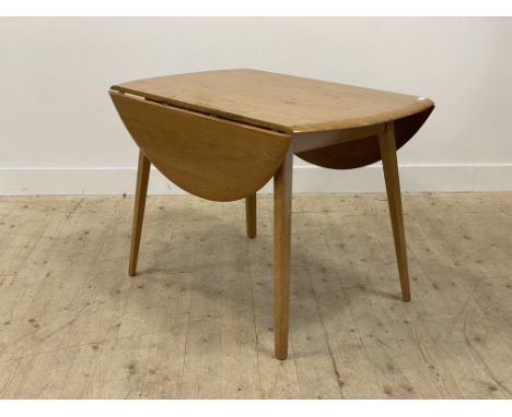 A mid century oak drop leaf dining table by Priory, in the Ercol style, the circular top raised on tapered and splayed suppor