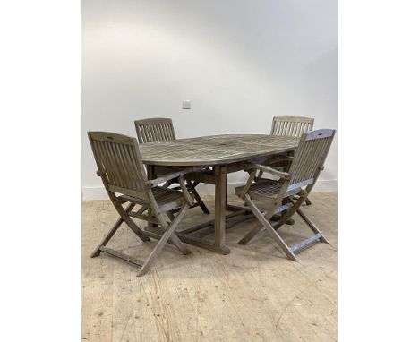 A silvered teak garden suite, comprising an extending garden table, the slatted oval top with magic leaf under, raised on squ