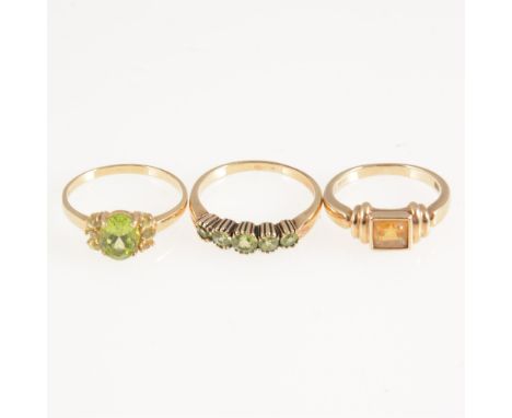 Three stone set dress rings, a peridot five stone half hoop mount in all yellow metal marked 9K, ring size O, a peridot dress