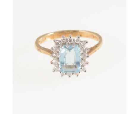 An aquamarine and diamond rectangular cluster ring, the emerald cut aquamarine 7mm x 6mm claw set and surrounded by sixteen e