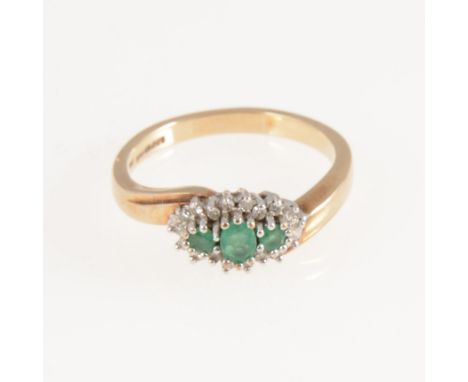 An emerald and diamond cluster ring, three emeralds claw set to the centre and surrounded by eighteen eight cut diamonds in a