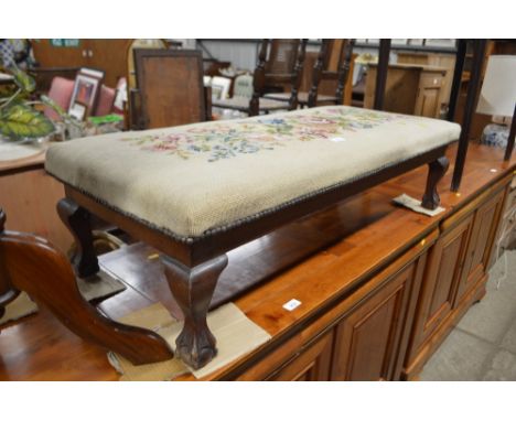 A mahogany and needlework upholstered oblong stool, raised on claw and ball supports 