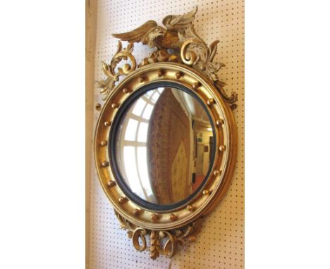 CONVEX WALL MIRROR, George IV giltwood with ebonised reeded slip and eagle crest, 60cm W x 90cm H. 