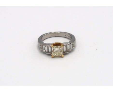 An 18ct gold and platinum ring designed as a fancy light yellow princess cut diamond with three graduating baguette cut diamo