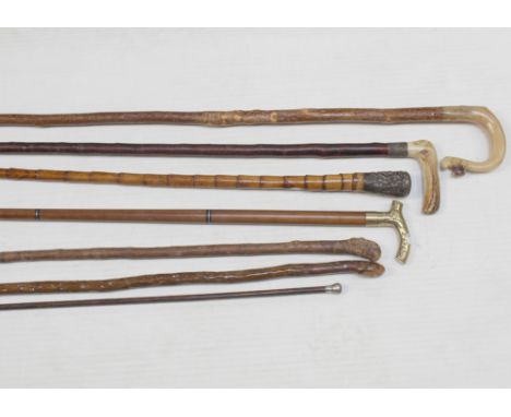 A small mixed group of walking sticks to include a steam-bent horn-handled crook with ram's head decoration, a brass-handled 