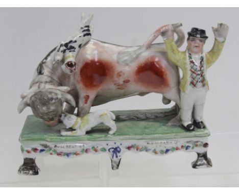 After Obadiah Sherrat; a c1830 figure of bull beating with figure of a bull with snarling dogs and bull baiter on a green sty