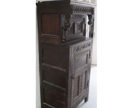 A late 18th/early 19th century oak court cupboard, carved top panel, floral carved frieze with carved face to either side ove