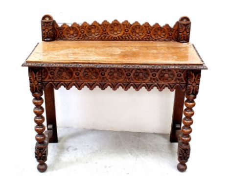 A late Victorian heavily carved oak side table with galleried back and supported on bobbin-turned legs, width 104cm.