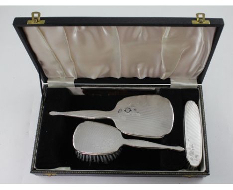 A George V case hallmarked silver dressing table set, hand mirror, two brushes and a silver topped comb, Adie Bros, Birmingha