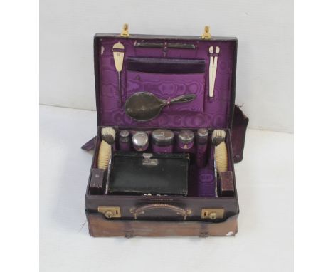 An early 20th century Harrods Ltd London burgundy leather ladies' travelling vanity case lined with purple moire silk and con