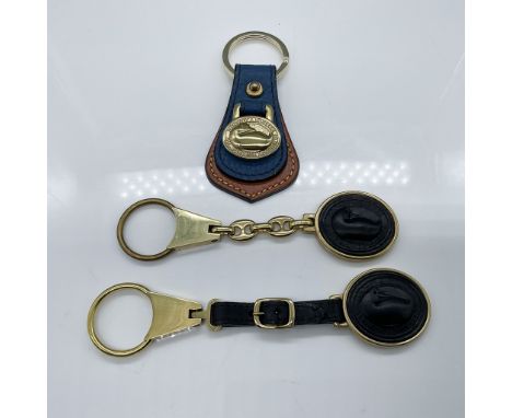 A 3-piece Dooney &amp; Bourke key fob set featuring a leather and gold-tone key fob with the iconic duck logo, accompanied by