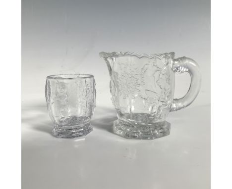 A clear sugar jar and creamer decorated with low relief art featuring characters from nursery rhymes and storybook trees. Dim