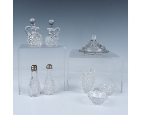 This charming set features intricately patterned clear glass pieces, including a covered dish, a pitcher, two cruet sets with