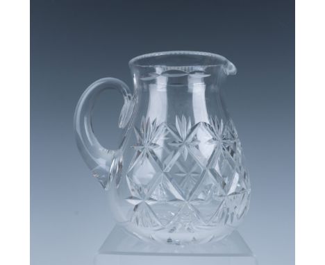 A dazzling small glass pitcher featuring a star and diamond-shaped cut pattern, with a smooth handle. Dimensions: 6"L x 5"W x