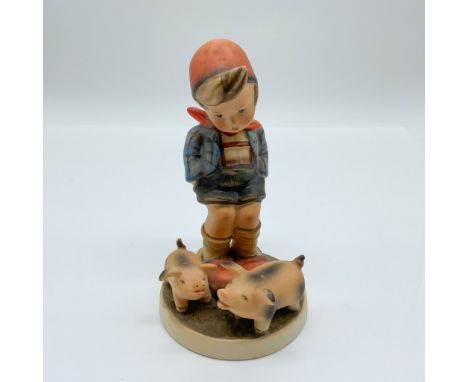 This Hummel porcelain figurine, titled "Farm Boy," depicts a young boy in a red cap and blue plaid shirt standing alongside t