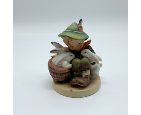 This lot features a Hummel figurine titled "Playmates," which depicts a young boy seated with a basket of rabbits. He is dres