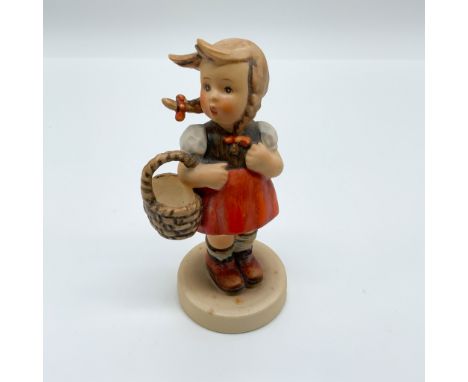 This charming Hummel porcelain figurine, titled "Little Shopper," portrays a young girl holding a basket, dressed in a tradit