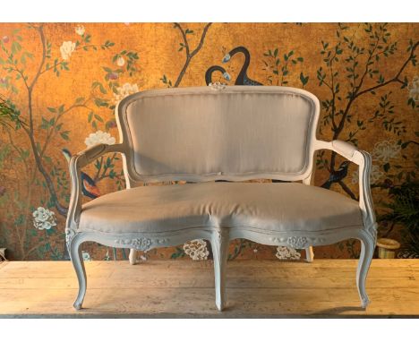 A SMALL FRENCH LOUIS XV STYLE PAINTED WOOD CANAPE SOFAnewly upholstered in cream linen, the white painted frame with scrollin