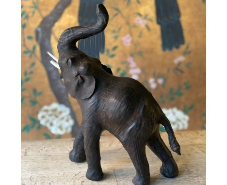 A LIBERTIES STYLE LEATHER COVERED MODEL OF AN ELEPHANTthe elephant with trunk raised, with glass eyes,40cm high