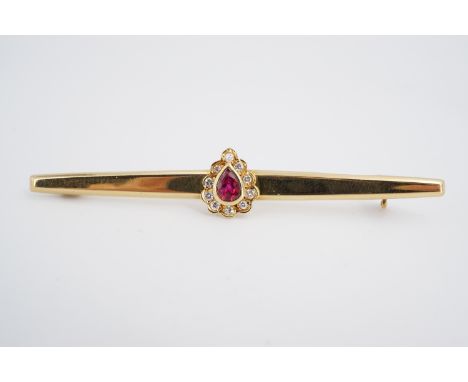 A 14ct gold, diamond and ruby bar brooch, with central pear cut ruby of approximately .30ct, rub set and framed by ten brilli